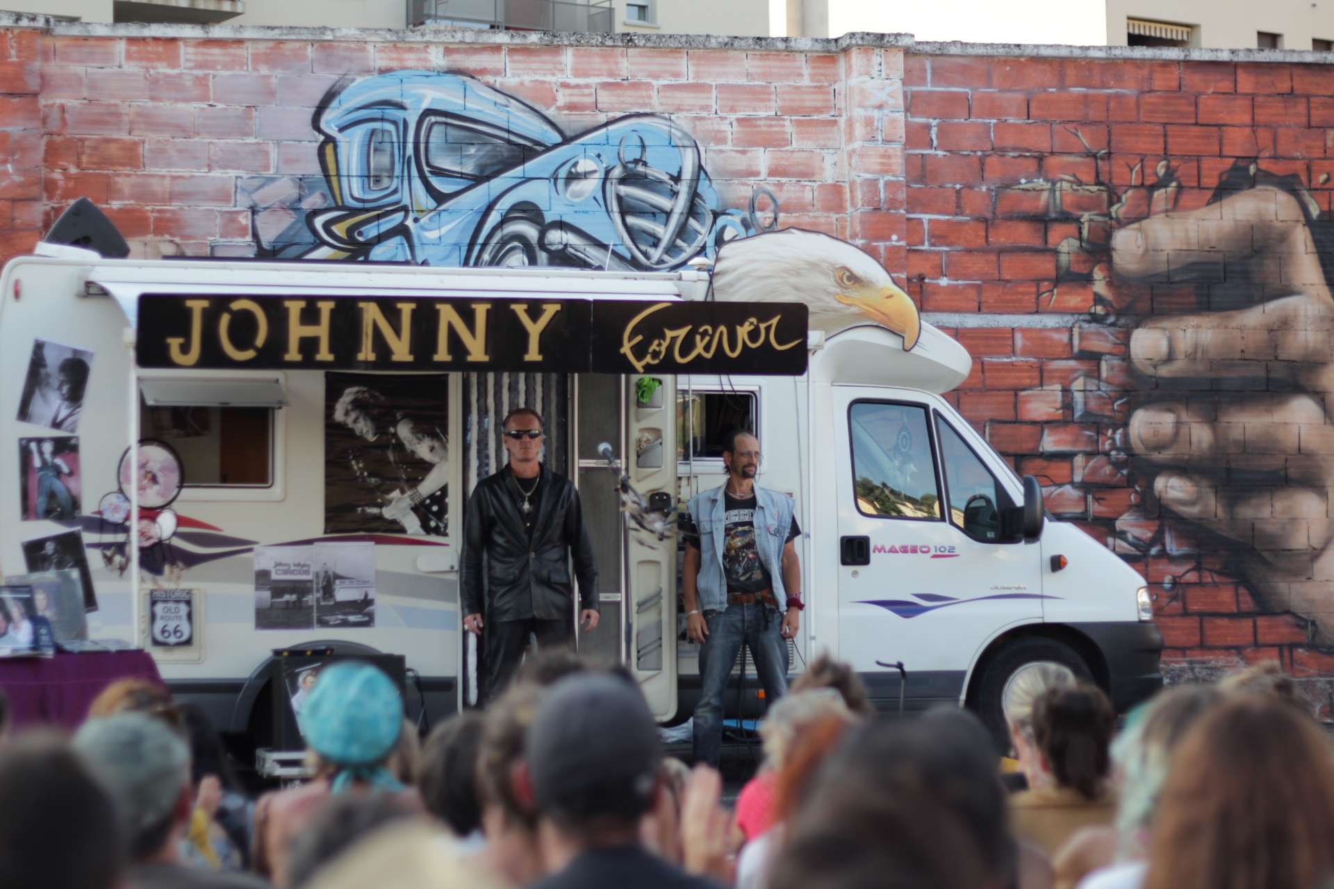Un camping car est montré avec deux garde du corps. L'écriture "Johnny forever" est inscrite sur le camping-car.