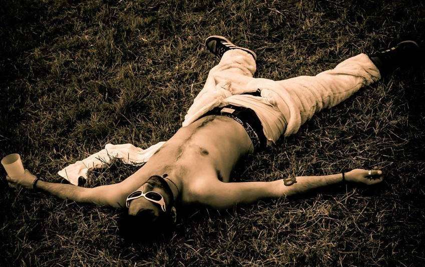 Un homme est couché dans l'herbe, torse nu, avec un jogging en fourrure.