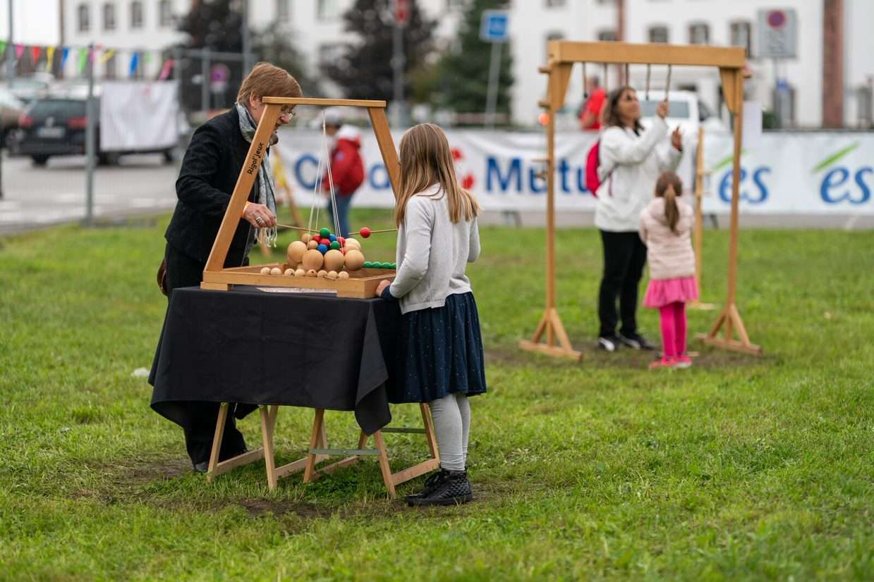 On voit un enfant et son parent jouer à des jeux en bois.